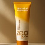 طراحی تیوب کرم دست ایستاده روی زمین با زمینه ای به رنگ قهوه ای و نور ملایم افتاب روی محصول. رنگ درب تیوب قهوه ای و بدنه تیوب از بالا گردینت زرد به کرم است